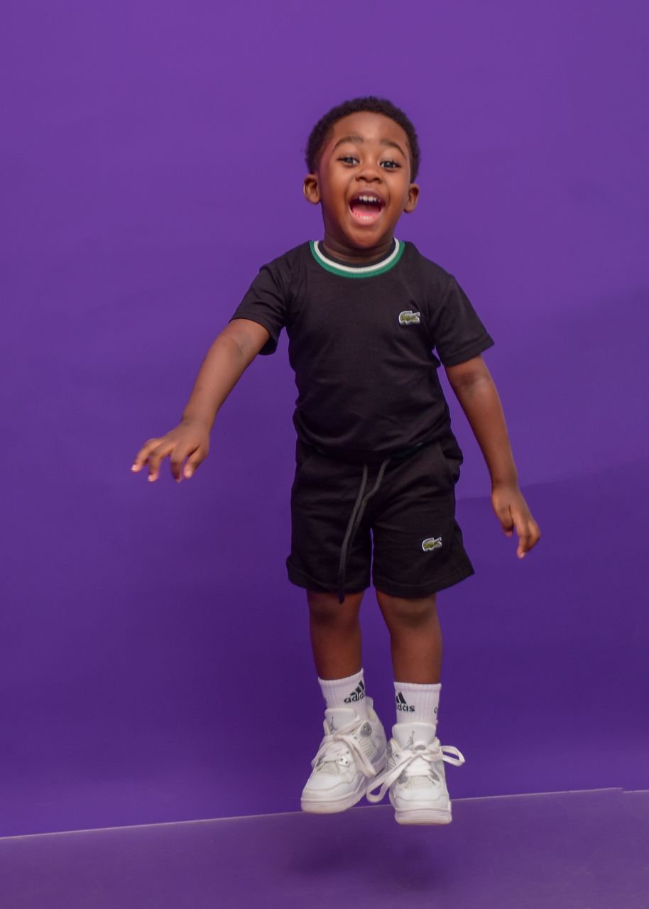 Joyful child mid-jump wearing a stylish black two-piece set from Kozykids Grove